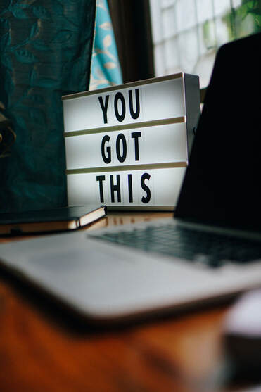Desk with laptop and sign saying you got this